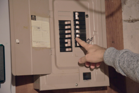 a hand pointing on an electrical panel